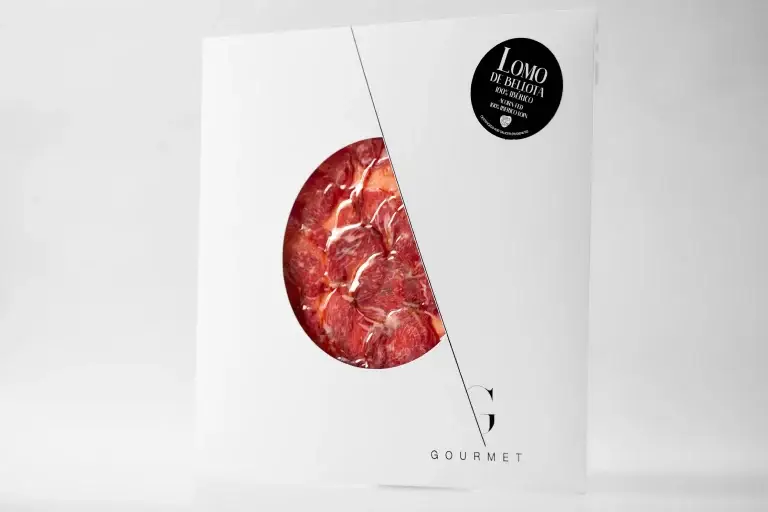 Lomo de Bellota 100% Ibérico de Guijuelo Gourmet presentado en un sobre cuadrado blanco con un diseño de círculo recortado en el centro. En la esquina superior derecha, se encuentra una etiqueta negra que identifica el producto.