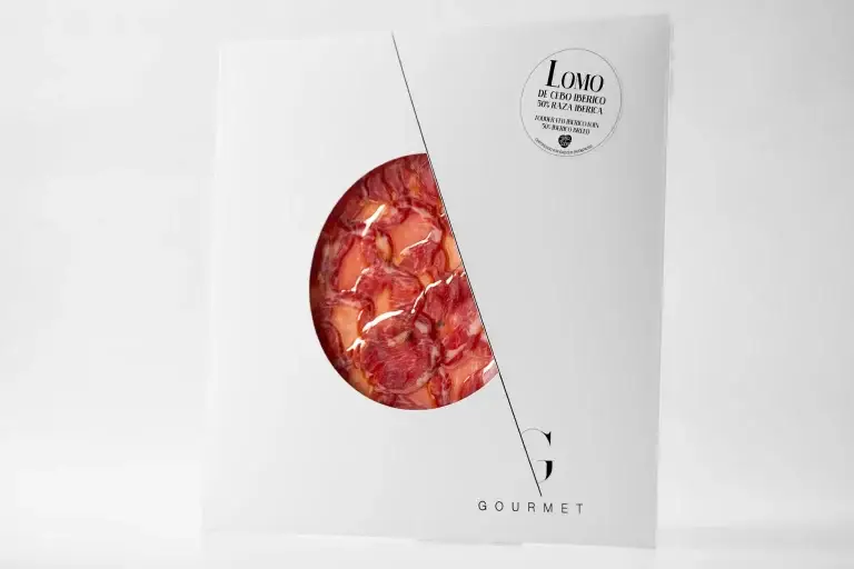Lomo de Cebo 50% Ibérico de Guijuelo Gourmet presentado en un sobre cuadrado blanco con un diseño de círculo recortado en el centro. En la esquina superior derecha, se encuentra una etiqueta blanca que identifica el producto.
