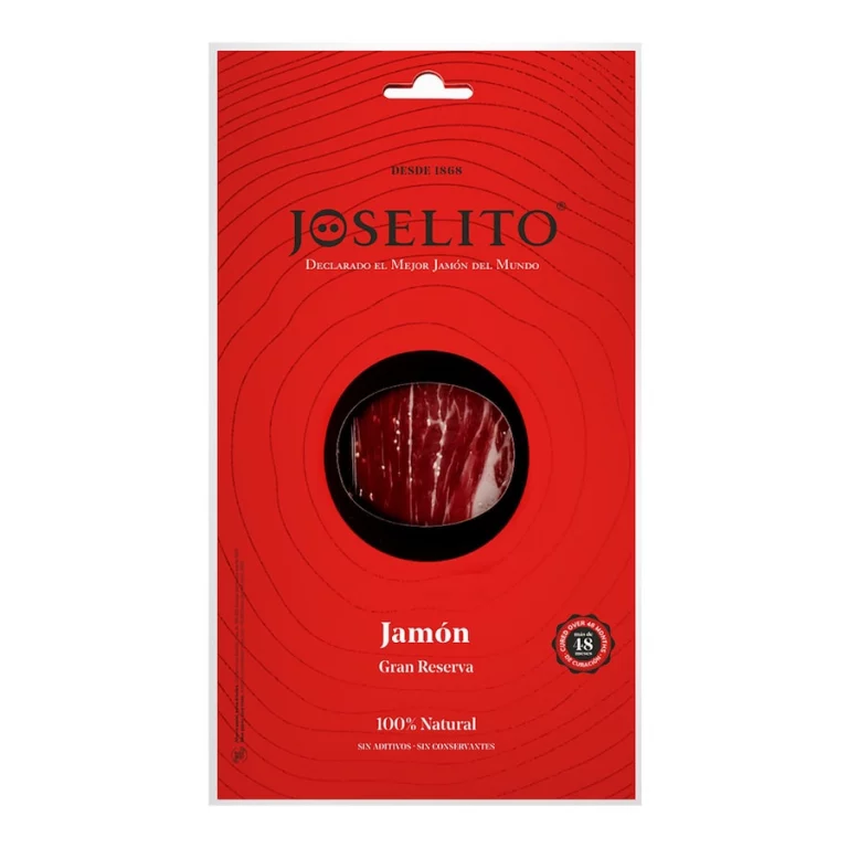 Un sobre rojo con un corte circular en el centro, mostrando jamón Joselito Gran Reserva loncheado envasado al vacío, con finas lonchas de color rojo intenso y un veteado de grasa brillante, resaltando su textura suave y sabor excepcional.