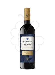 Botella de vino tinto de color negro con un sello de cápsula dorado, donde se lee "Marqués de Vitoria Bodegueros desde 1861". En la etiqueta de la botella, de color azul oscuro, aparece el nombre de la marca en negro, seguido de un pequeño texto dorado que dice "Gran Reserva 2015" y la denominación de origen "Rioja".