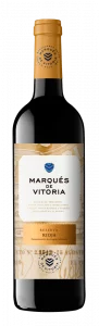 Botella de vino negra con cápsula dorada, en la que aparece el texto "Marqués de Vitoria Bodegueros desde 1861". La etiqueta en el cuerpo de la botella es dorada, con el nombre de la marca "Marqués de Vitoria" en negro, seguido de la indicación "Reserva 2018" en dorado y la denominación de origen "Rioja".