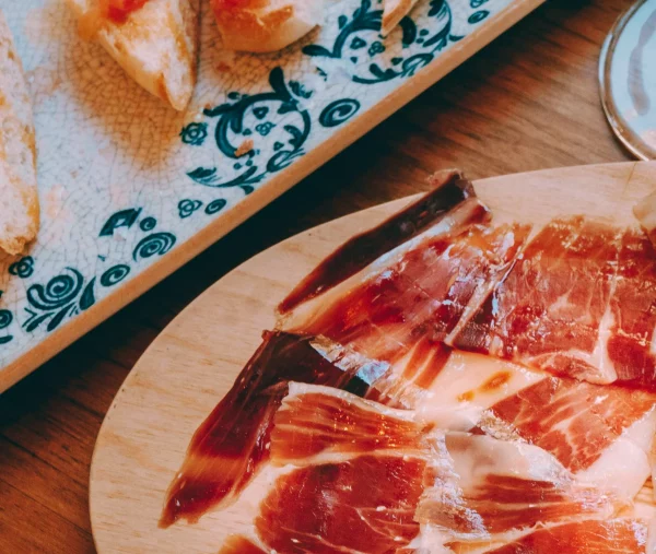 Un plato de jamón loncheado delicioso y un plato de pan con tomate